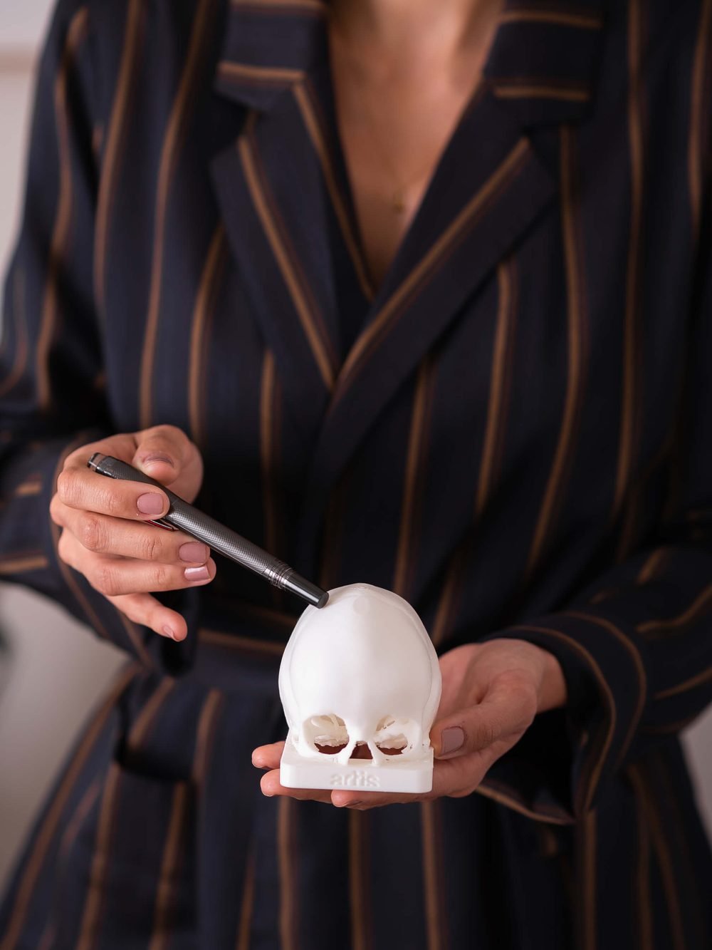 Dra. Leyzeane analisando um modelo de crânio impresso em 3D para planejamento cirúrgico
